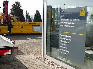 Schild an einer Glasfassade des ADAC Mobilit&auml;tspartners Peter in Nordhausen. Das Schild listet angebotene Leistungen auf, wie Pannen- und Unfallhilfe, Autovermietung, Schadenservice sowie Partnerleistungen wie Fahrzeugreparatur, Unfallreparatur, Glas- und Reifenservice, Autovermietung und Kranservice. Im Hintergrund ein gelber ADAC-Abschleppwagen.