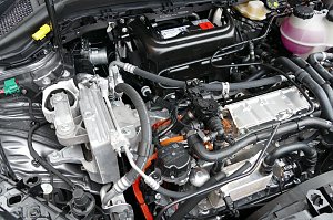 Blick in den Motorraum eines E-Fahrzeuges. Gut zu erkennen sind die Hochvolt-Trennstelle (gr&uuml;n) und die HV-Kabel (orange). 