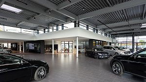 Heller Mercedes-Benz Schauraum mit mehreren ausgestellten Fahrzeugen, moderner Architektur, großen Glasfronten und industriellem Deckenstil.