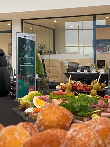 Nahaufnahme eines Buffets mit belegten Br&ouml;tchen, Obst, Gem&uuml;se und K&auml;seplatten. Daneben steht ein Begr&uuml;&szlig;ungsaufsteller zum �koda Unternehmerfr&uuml;hst&uuml;ck.