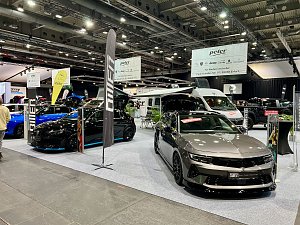 Zwei moderne Opel-Modelle, ein schwarzer und ein grauer Wagen, stehen auf der Ausstellungsfl&auml;che der Autohaus Peter Gruppe. Im Hintergrund Wohnmobile und gro&szlig;e Banner.