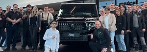 Jamil aus der TV-Show �The Voice Kids� steht mit einem Daumen-hoch-Zeichen vor einem schwarzen Mercedes-Gel&auml;ndewagen im Autohaus Mercedes Wittenberg, umgeben von Mitarbeiterinnen und Mitarbeitern des Autohauses.