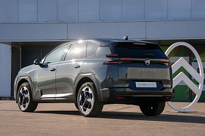 Schräg-hinten-Ansicht des neuen Citroën C5 Aircross vor einem Gebäude mit großem Citroën-Logo.