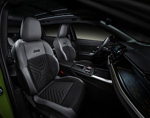 Innenraumaufnahme des Jeep Compass – Vordersitze in schwarz-grauer Lederoptik mit Jeep-Logo, moderner Instrumententafel und großem Panoramadach.