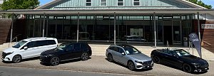 Vor der Stadthalle Wittenberg sind vier Mercedes-Benz-Fahrzeuge in einer Reihe ausgestellt: ein wei&szlig;er Van, ein schwarzer SUV, ein silberner Kombi und ein schwarzes Cabriolet mit offenem Verdeck. Rechts steht eine schwarze Fahne mit dem Logo Autohaus Peter.