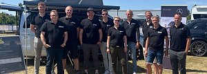 Gruppenfoto des Teams vom Autohaus Peter bei sonnigem Wetter. Zehn Personen stehen in schwarzer Teamkleidung mit Logo �Peter� nebeneinander vor einem silbernen Van und einem schwarzen Mercedes. Im Hintergrund sind ein Zelt, Werbebanner und weitere Fahrzeuge zu sehen. Alle l&auml;cheln in die Kamera.