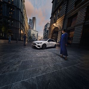 Das Bild zeigt einen wei&szlig;en Mercedes-Benz CLA Shooting Brake, der auf einer breiten, nahezu leeren Stadtstra&szlig;e f&auml;hrt. Moderne Geb&auml;ude umgeben die Szene, das Licht wirkt weich und fr&uuml;hmorgendlich. Der Wagen ist seitlich zu sehen und vermittelt Dynamik sowie Eleganz.