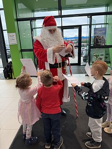 Die Kinder geben dem Weihnachtsmann ihre gemalten Wunschzettel