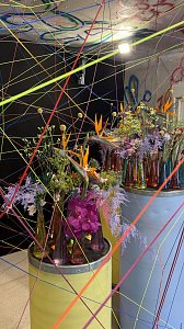Kunstvoll inszenierte Blumenarrangements und viele bunte, durch den Raum gespannte Bindf&auml;den.