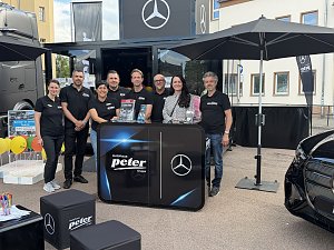 Man sieht das Autohaus Peter Team am Freitagnachmittag nach dem Aufbau des Standes. Sie stehen an und hinter einem Counter.