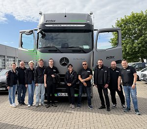 Team Peter steht in gleichen schwarzen Poloshirts vor dem eActros.