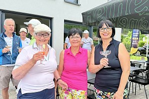 Drei Golferinnen posieren mit Getr&auml;nken vor dem Clubhaus w&auml;hrend der Veranstaltung.