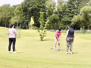 Drei Golferinnen auf dem Gr&uuml;n beim Putten in sommerlicher Atmosph&auml;re.