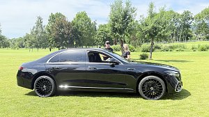 Schwarze Mercedes-Benz Limousine wird auf dem Golfplatz pr&auml;sentiert, zwei Personen stehen daneben.