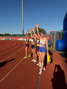 Vier strahlende Athletinnen, darunter Gina L&uuml;ckenkemper (Startnummer 201) und Sina Mayer (Startnummer 204), jubeln mit erhobenen Armen auf der Laufbahn im Paul-Greifzu-Stadion.