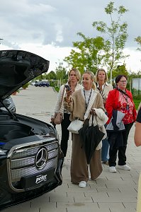 Mehrere Frauen, die im Freien hinter dem ge&ouml;ffneten Frunk eines Mercede-Benz GLC stehen und das Auto betrachten.