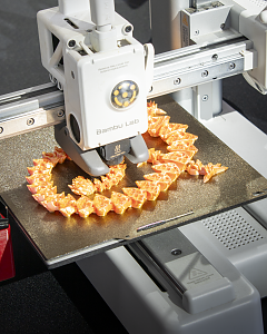 3D-Drucker bei der Herstellung mehrerer kleiner orangefarbener Drachenfiguren.