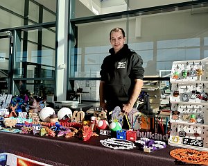 Aussteller hinter einem Verkaufsstand mit handgefertigten Dekorationsartikeln, Figuren und bunten Schl&uuml;sselanh&auml;ngern beim Aktionstag der Autowelt Peter.