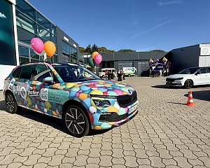 Farbenfroh folierter �koda mit buntem Luftballonmotiv auf dem Au&szlig;engel&auml;nde der Autowelt Peter, im Hintergrund H&uuml;pfburg und Veranstaltungsbereich.