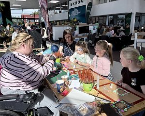 Kinder und Erwachsene gestalten gemeinsam kreative Bastelarbeiten an einem gro&szlig;en Tisch w&auml;hrend des Familienprogramms im �koda-Autohaus.