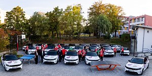 Spielerinnen des Th&uuml;ringer HC in roten Trikots und Vertreter der Peter Gruppe stehen zwischen gebrandeten Opel-Fahrzeugen auf einem Sportgel&auml;nde.