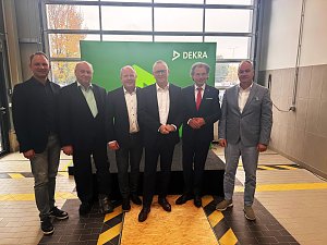 6 Personen im Anzug stehen vor einem gr&uuml;nen Dekra Banner