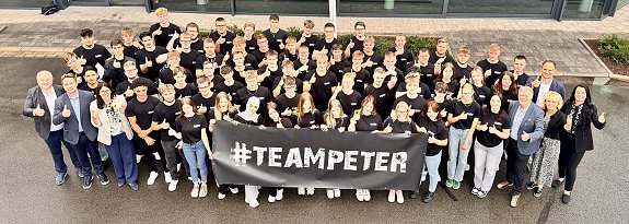 Gruppenfoto der 63 neuen Auszubildenden der Autohaus-Peter-Gruppe vor dem Mercedes-Benz-Autohaus in Nordhausen. Alle tragen schwarze #TeamPeter-T-Shirts und halten einen Banner mit dem Schriftzug �#TEAMPETER�. Gesch&auml;ftsf&uuml;hrung und Ausbildungsleitung stehen am Rand, alle l&auml;cheln und zeigen Daumen hoch.