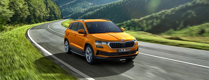 orangenes Auto f&auml;hrt eine Landstra&szlig;e entlang